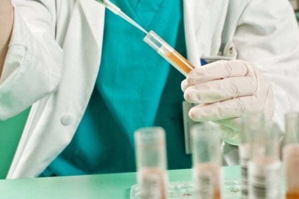 A person in white lab coat holding a syringe.