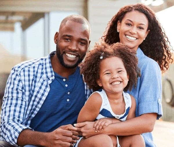 A family of three is smiling for the camera.