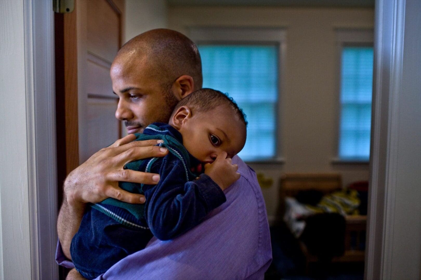 A man holding his son in the arms of another man.