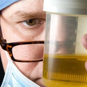 A person holding a container of urine in front of their face.