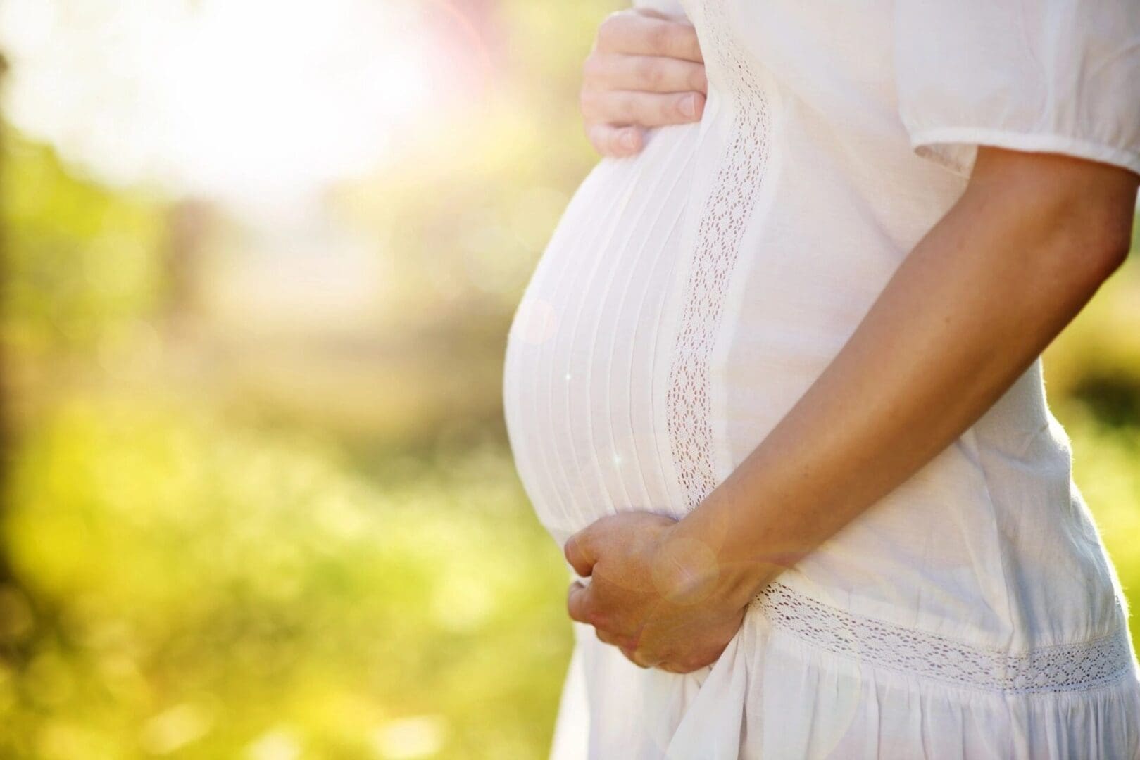 A pregnant woman standing outside in the sun.